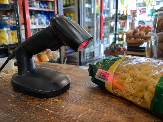 Lector de código de barras de mano escaneando un paquete sobre el mostrador