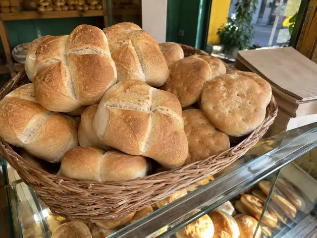 Canasto de marraquetas y hallullas recién horneadas en la vitrina de una panadería